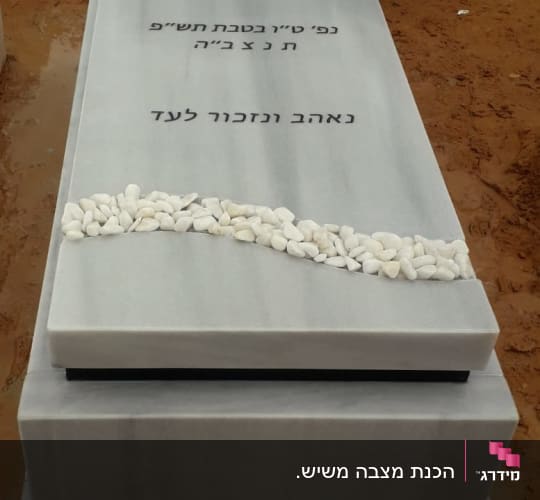 מצבה עם כיתוב בעברית ואבנים לבנות